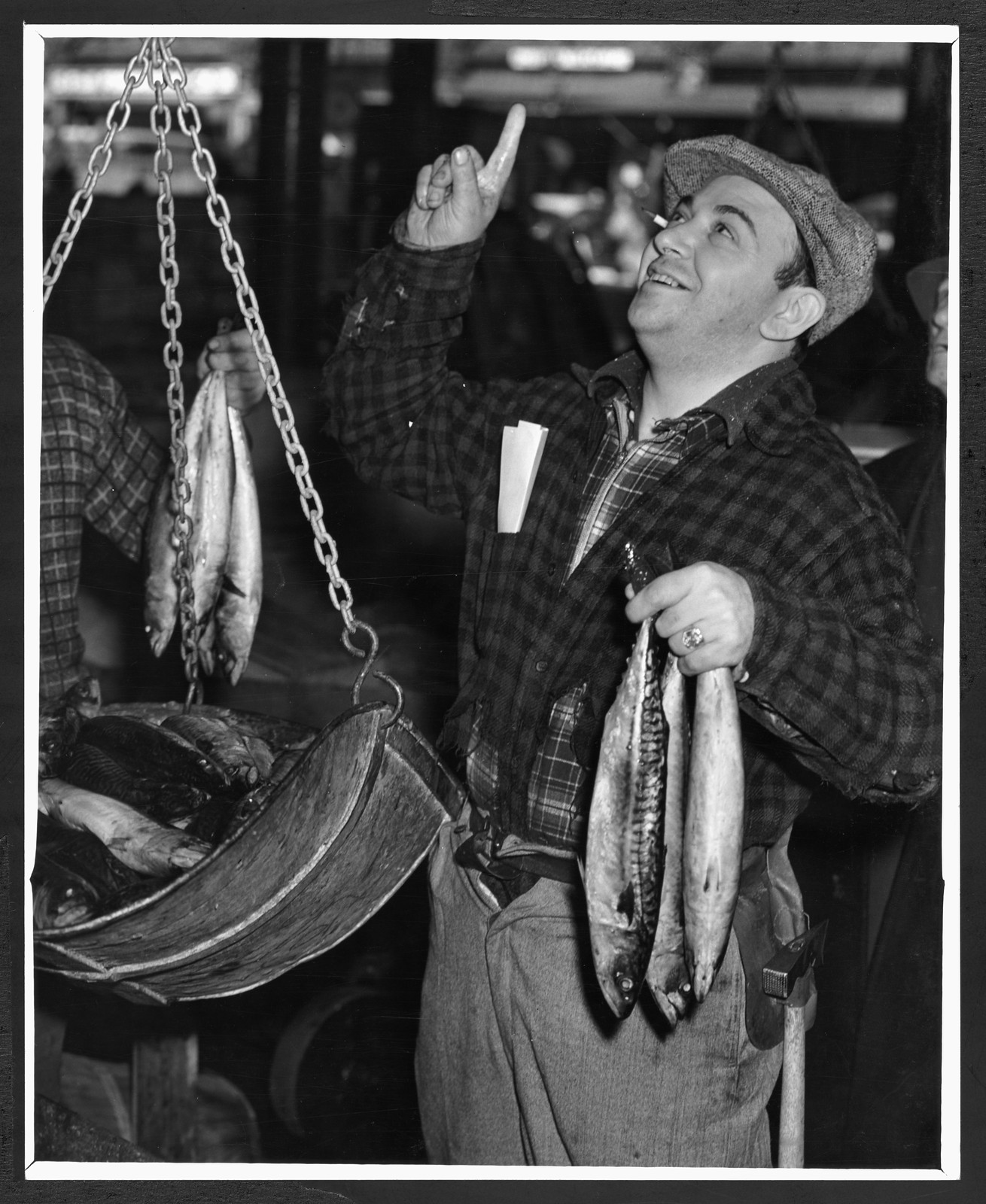 Man weighing fresh mackerel at a fish market — historic image