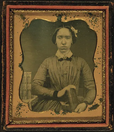 Unidentified Woman Holding Book, With Books on Table to Her Right
