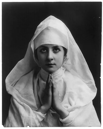 [Young woman modeling: Half lgth., wearing nun's white habit and praying]