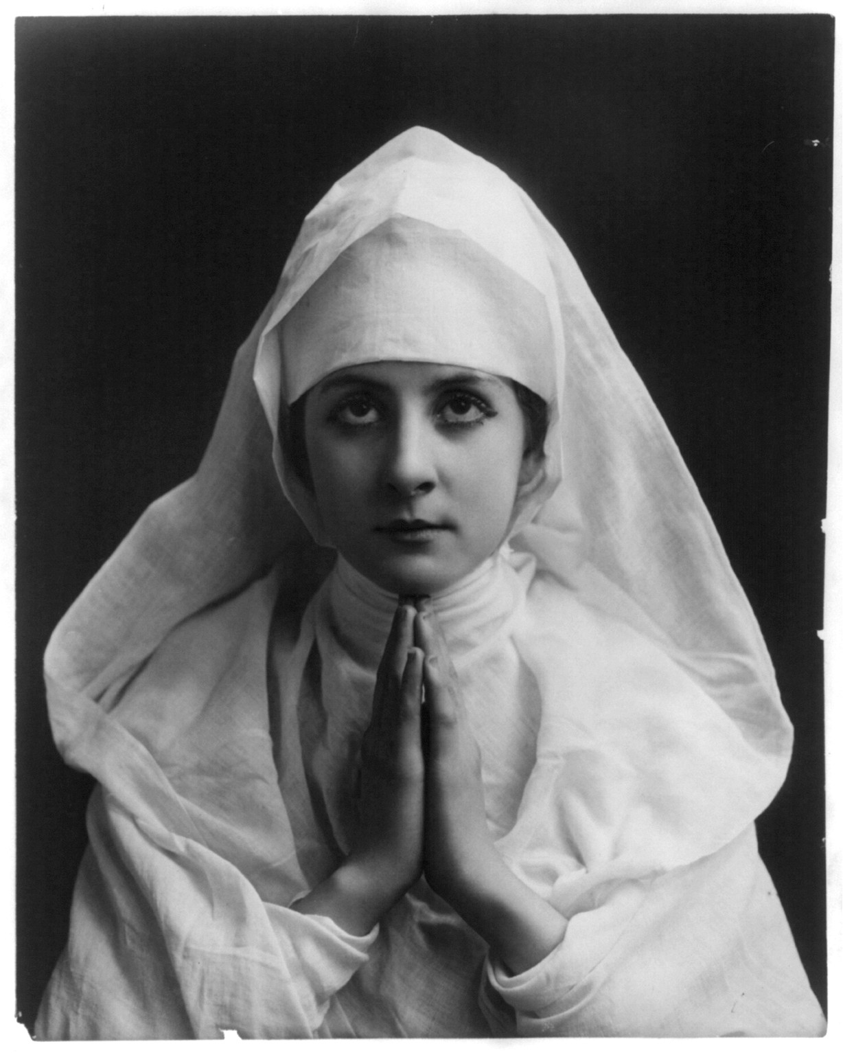 [Young woman modeling: Half lgth., wearing nun's white habit and praying], [no date recorded on caption card] — historic photograph