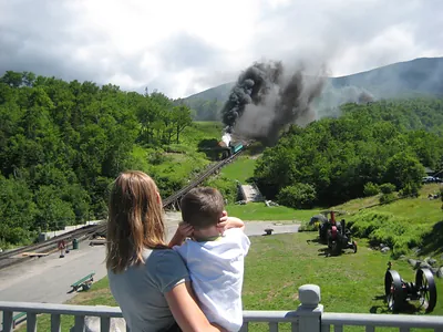 Woman and child watching a steam train emitting smoke