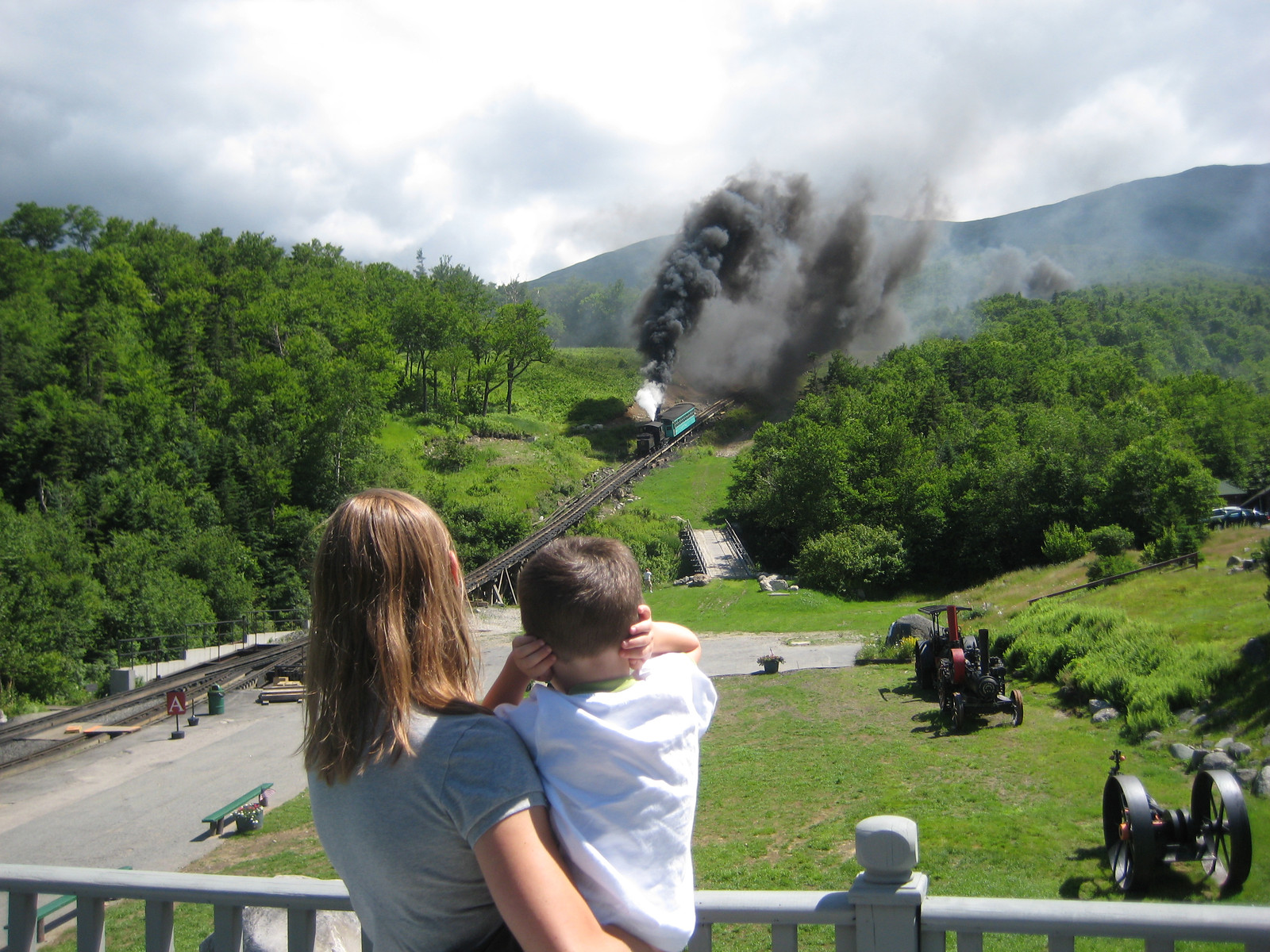 Woman and child watching a steam train emitting smoke — historic image