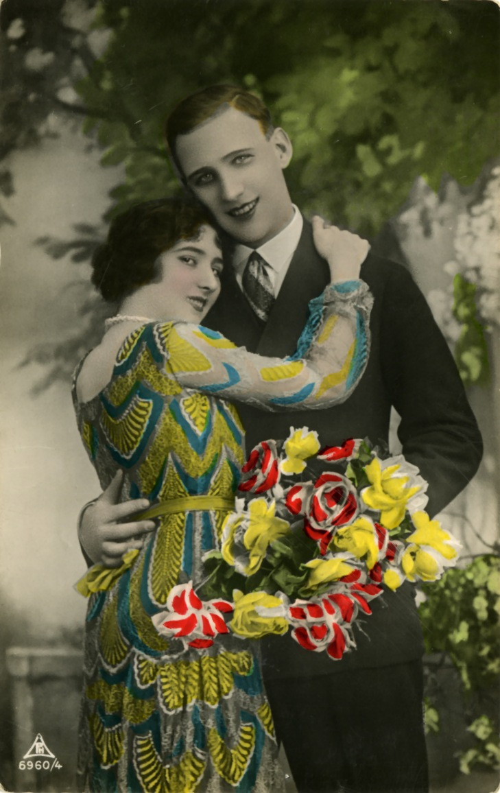 Hand-colored postcard of a couple embracing with a flower bouquet — vintage postcard