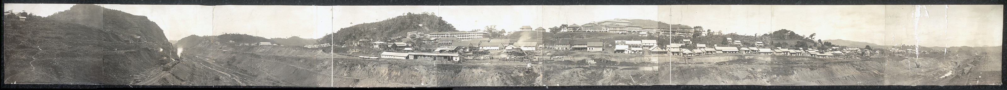 Panoramic view of a town beside an excavated cut — historic image