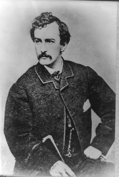 [John Wilkes Booth, half-length portrait, facing left and holding a cane]