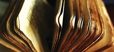 Close-up of fanned, aged book pages with worn edges