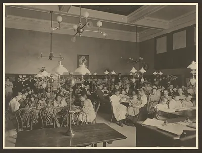 Children at tables in a library reading room, sepia photograph