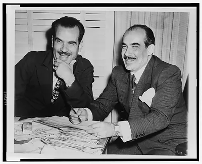 [President of Mexican Baseball League, Jorge Pasquel (left), and his brother Bernardo Pasquel (right), seated at table examining mail, Mexico City, Mexico