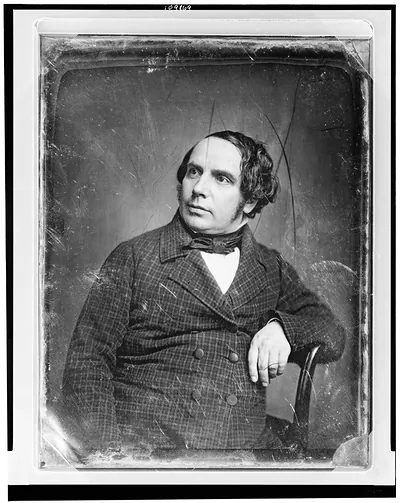 Seated man in plaid coat and bow tie, early photographic portrait