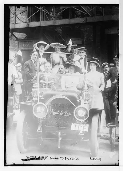 Motor Girls posing in and around Studebaker auto, going to baseball game