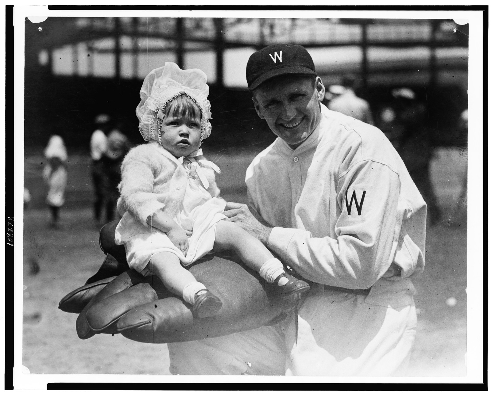 [Walter Johnson, half-length portrait, facing slightly left, holding little girl on large glove], [between 1909 and 1932] — historic photograph