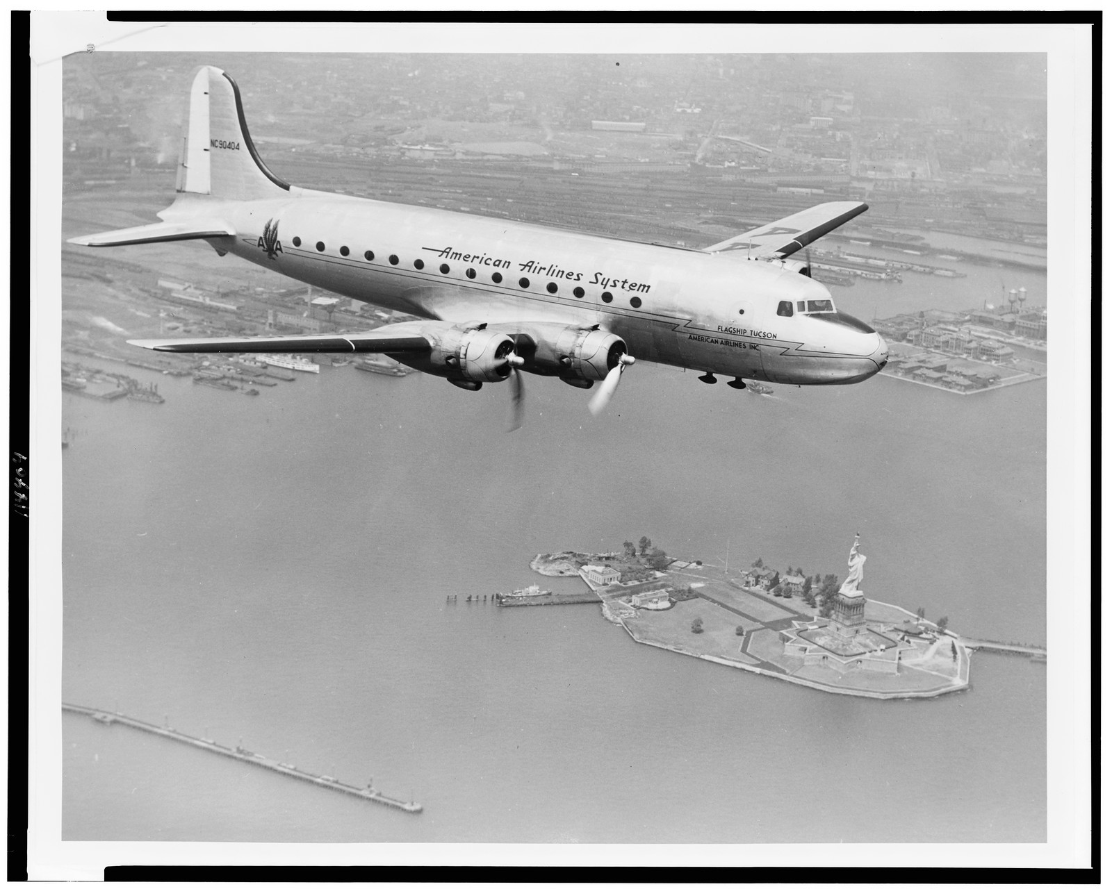 [Aerial view of American Airlines DC-4 Flagship, built by Douglas Aircraft Company, flying over Statue of Liberty], [between 1945 and 1950(?)] — historic photograph