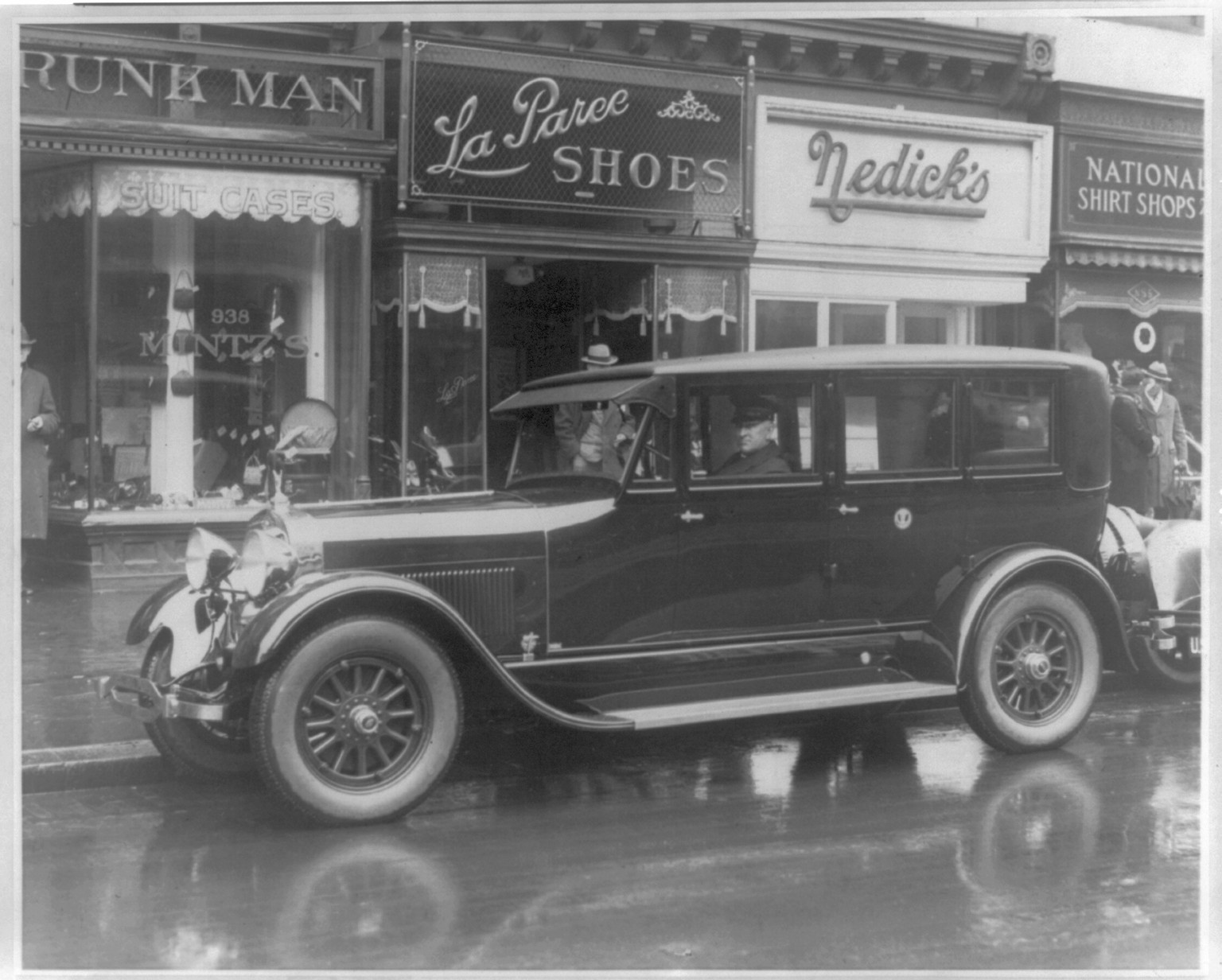 [Presidential automobile, ca. 1924 Lincoln, parked in front of stores, with the chauffeur seated behind the steering wheel] / photo by National Photo Co., [ca. 1924] — historic photograph