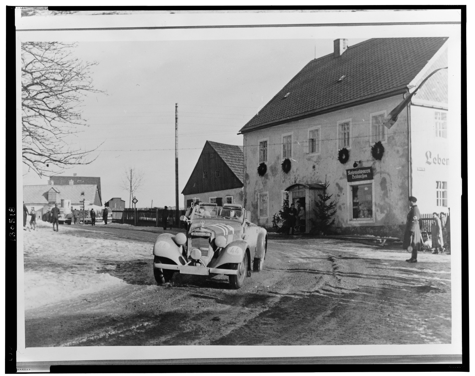 [Mercedes-Benz automobile passing in front of a building decorated with wreaths], 1938 — historic photograph