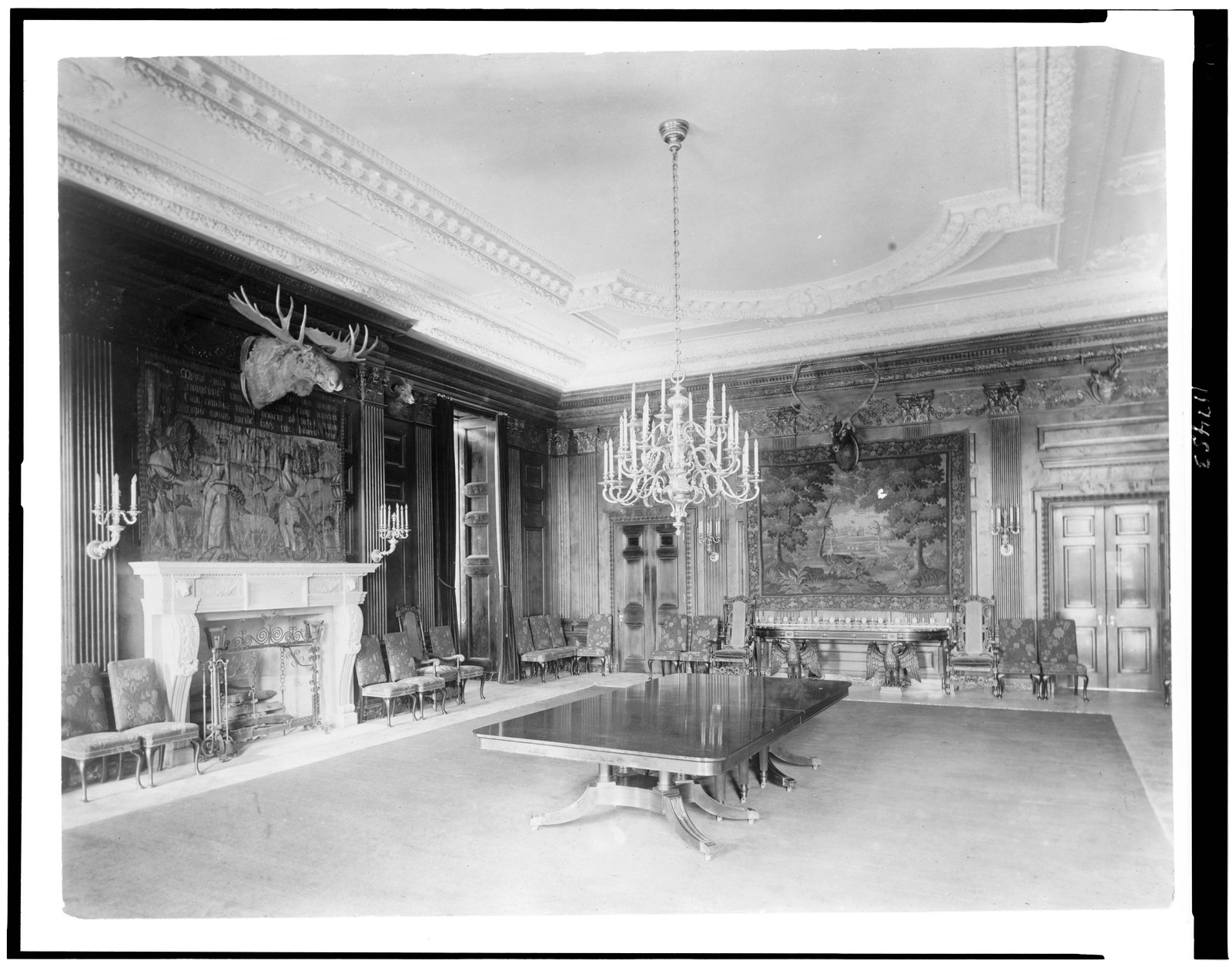 [Interior view of the White House, with moose head over fireplace, and chandelier above table], [1902] — historic photograph