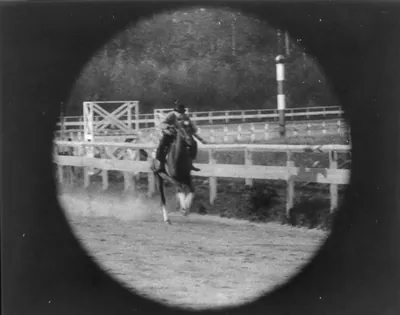Horse and rider jumping a rail fence, early film still