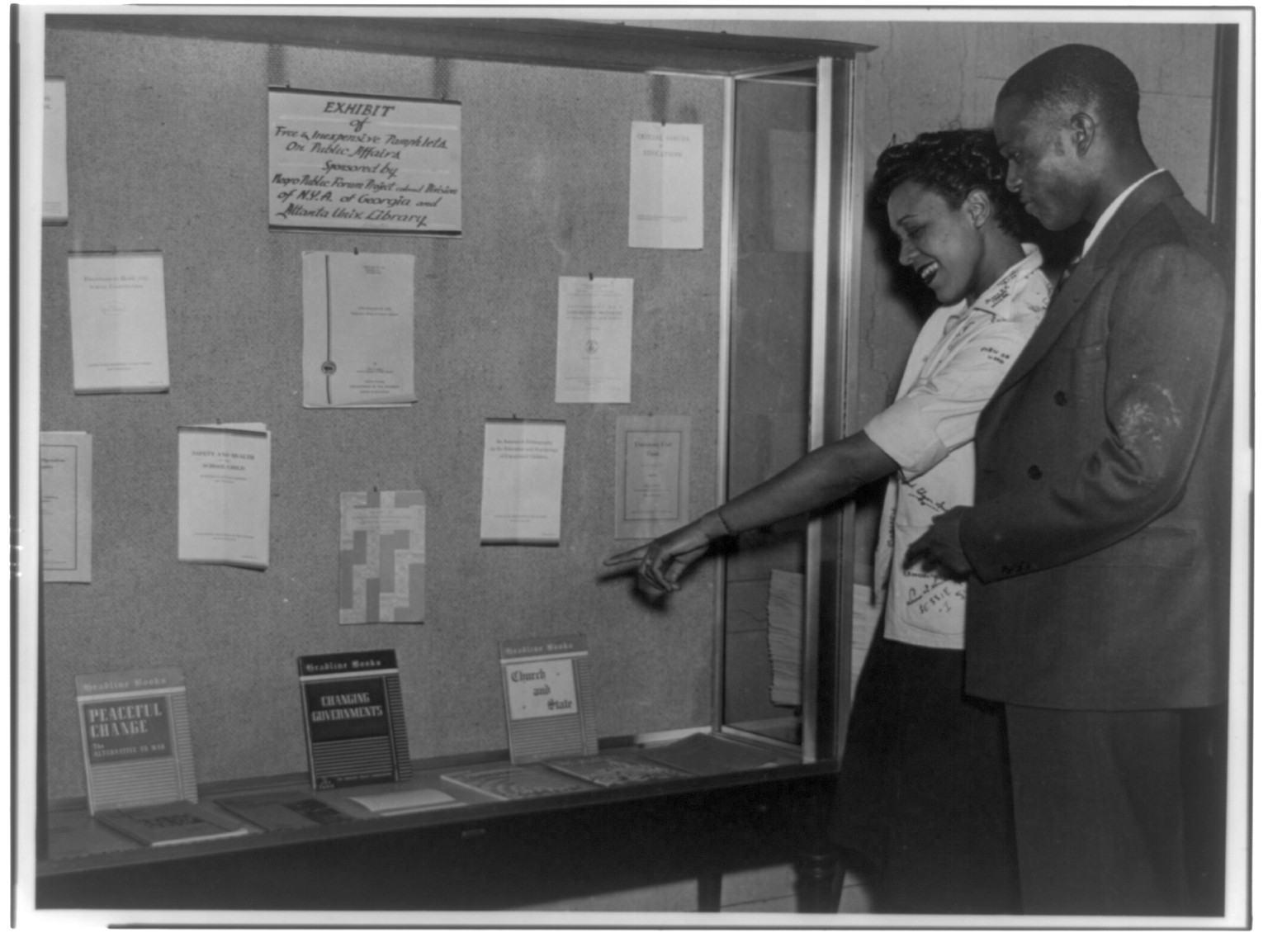 [Two black students at National Youth Administration library exhibit], [between 1935 and 1942(?)] — historic photograph