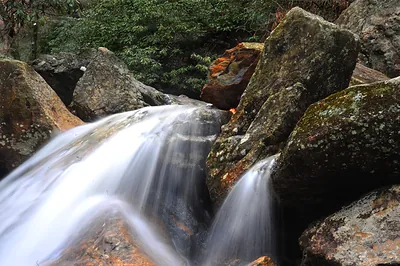 Long-exposure waterfall over mossy boulders