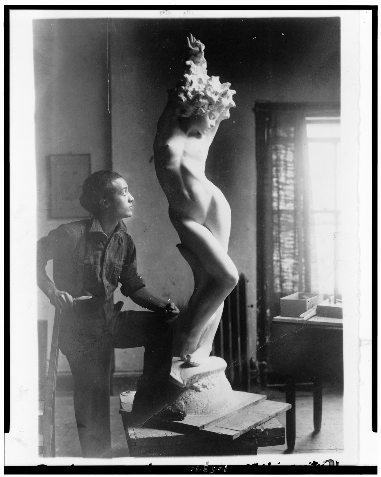 [Isamu Noguchi, full-length portrait, facing right, standing by his sculpture of a nude woman], c1927. — historic photograph