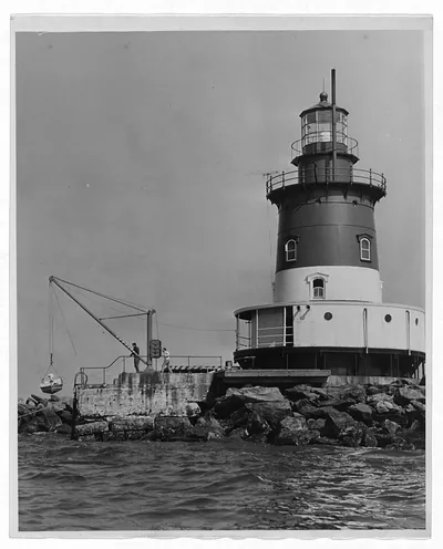 Lighthouse on rocks with crane and two men