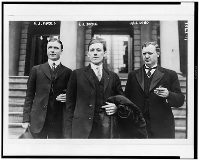 [Frank J. Hayes, E.L. Doyle, Jas. Lord, three-quarter length portraits, facing front, standing outside building]