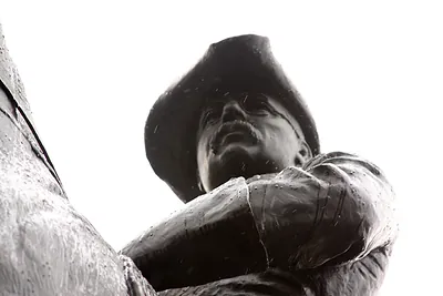 Bronze statue of a man in a tricorn hat, low angle