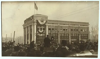 Speaker addressing a large crowd before a bunting-draped building