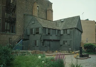 Wooden clapboard house in a courtyard garden behind brick buildings