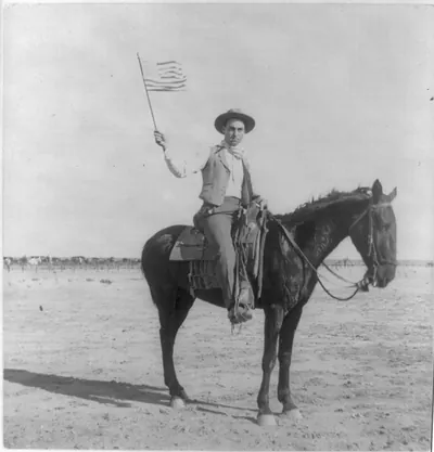 [Cowboy on horseback waving U.S. flag. Southwestern U.S.]