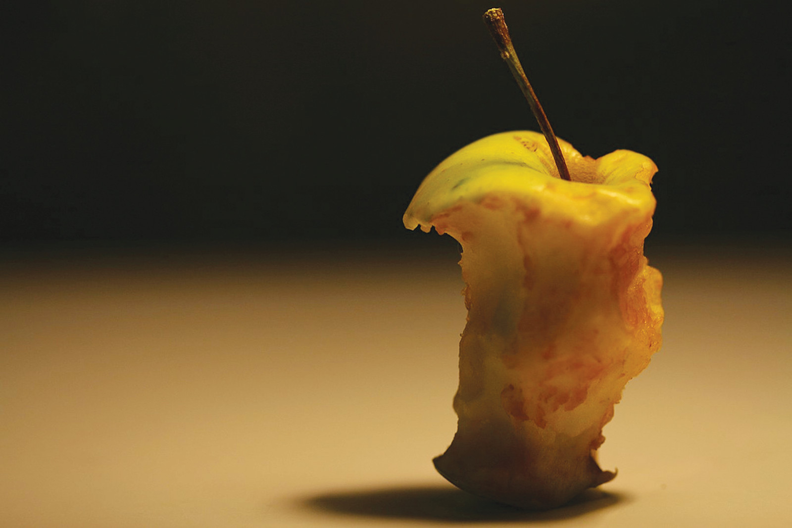 Bitten apple core with stem on dark background — historic image