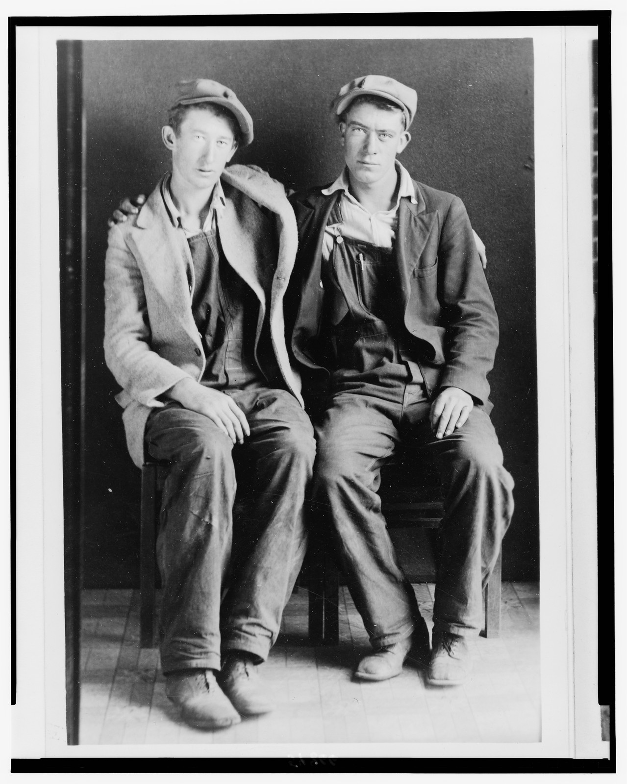 Southern Appalachian people, descendents of Europeans: 2 men in caps and overalls, full length, seated, with arms around each other, [between 1923 and 1943] — historic photograph