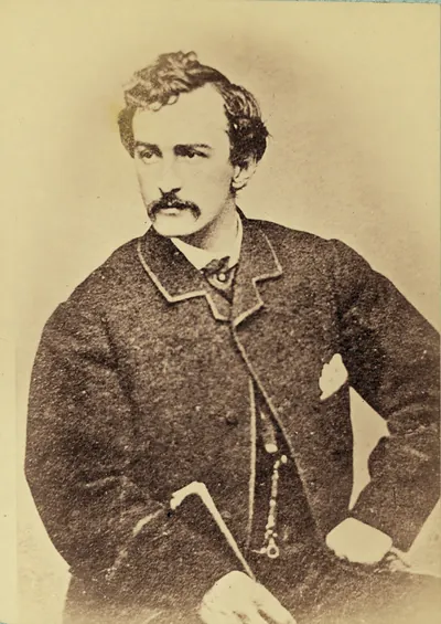 Sepia studio portrait of a young moustached man with cane