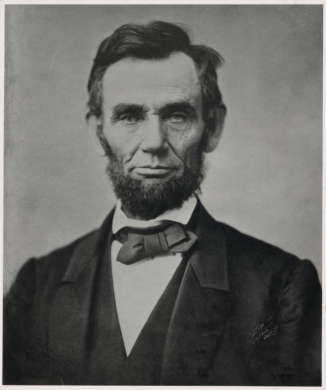 Photographic portrait of a bearded man in dark suit and bow tie — historic photograph