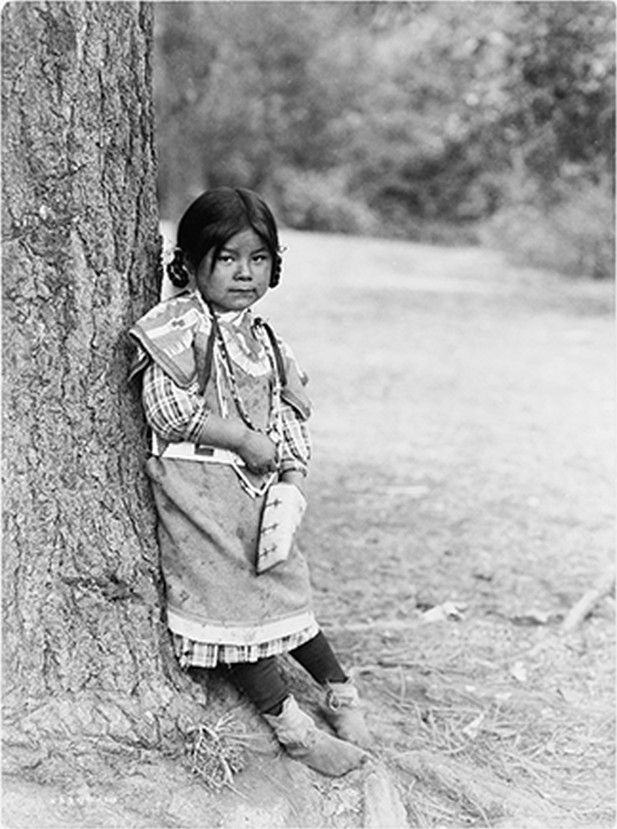 [Innocence, an Umatilla girl, full-length portrait, standing by tree, facing slightly right], c1910. — historic photograph