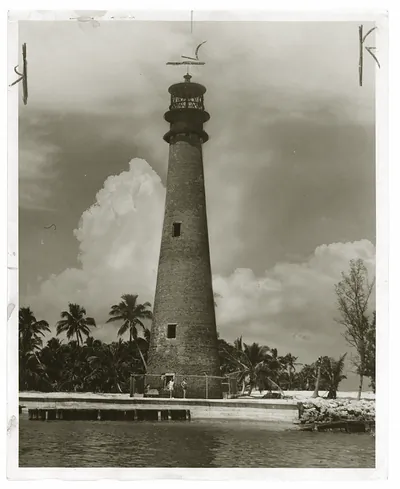 Brick lighthouse tower among palms, black-and-white photograph
