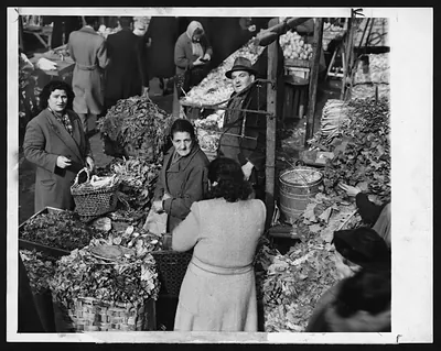 Market stall with leafy greens, baskets and shoppers