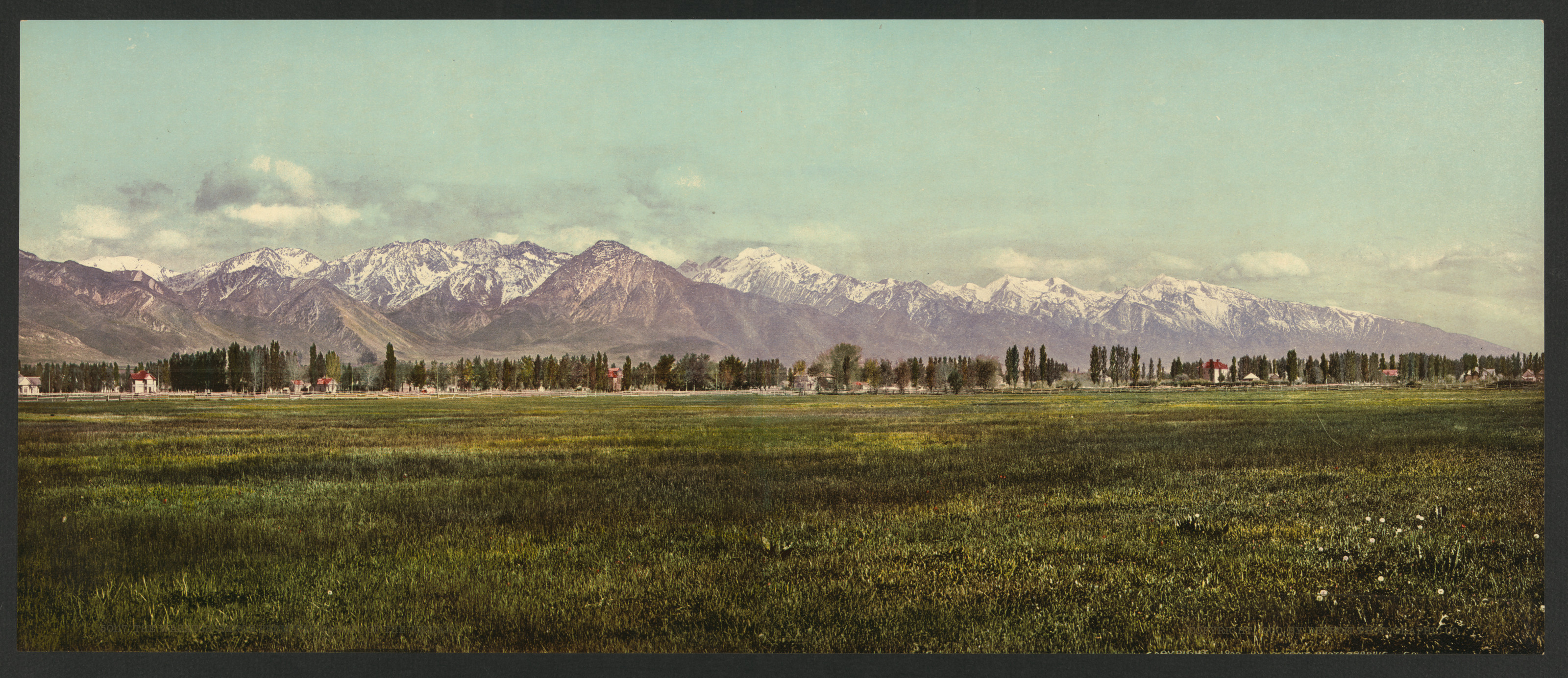 Snow-capped mountain range above a green valley meadow — historic image
