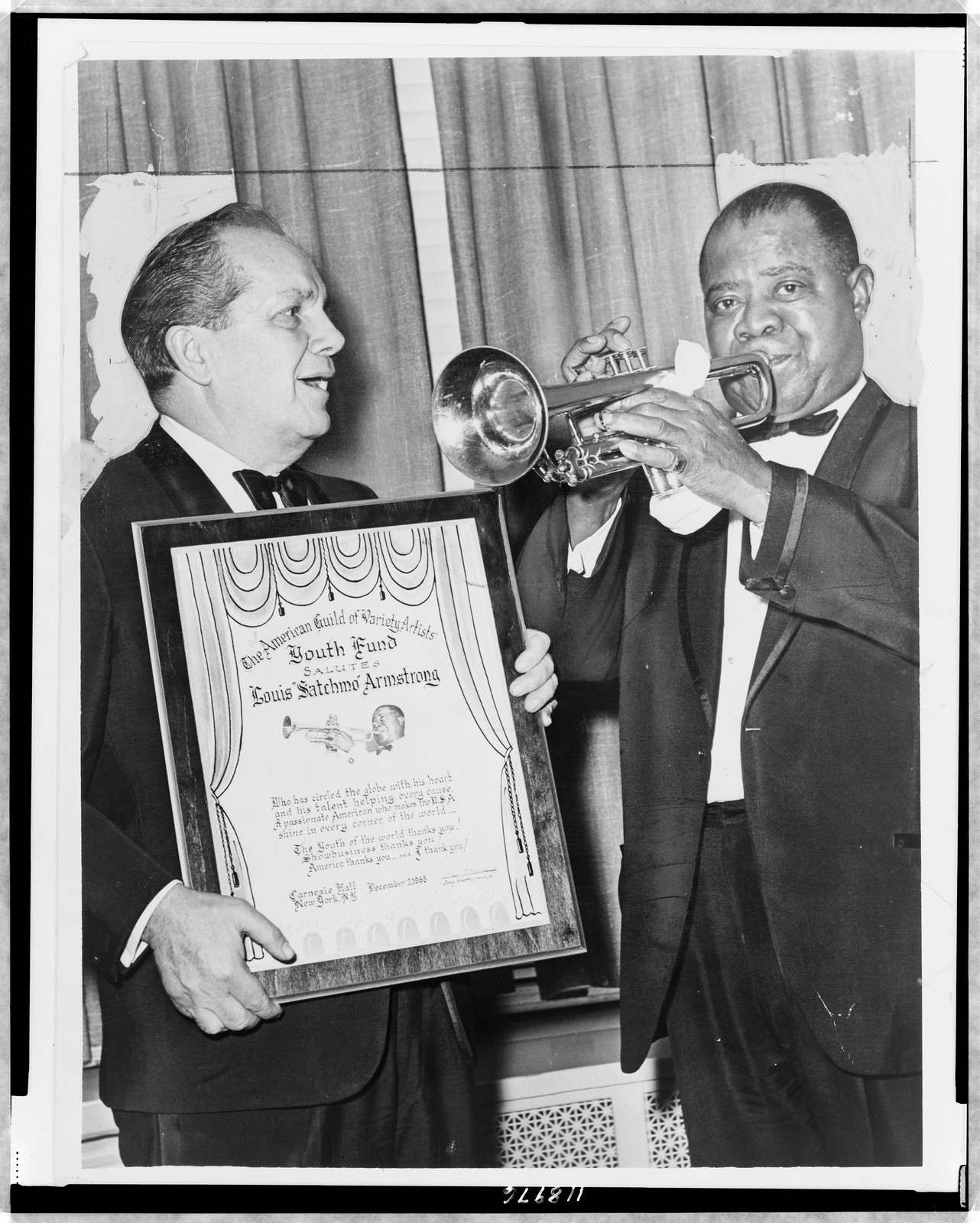 [Louis Armstrong plays trumpet while Joey Adams, president of the American Guild of Variety Artists Youth Fund, presents him with an award at Carnegie Hall], 1966 — historic photograph