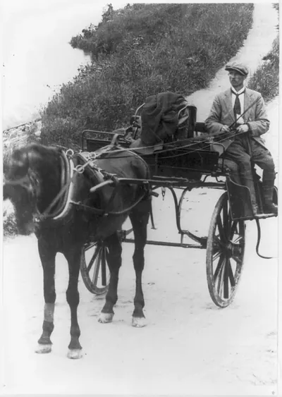 Man driving a horse-drawn jaunting car on a dirt road