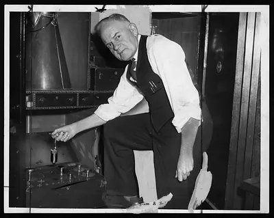 Man in vest adjusting a small weighing device indoors
