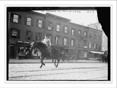 Horseback rider preceding railroad train on 11th Ave., New York City