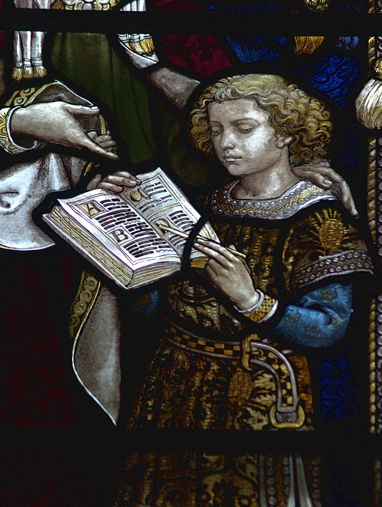 Stained glass detail of a boy with an alphabet book — historic image