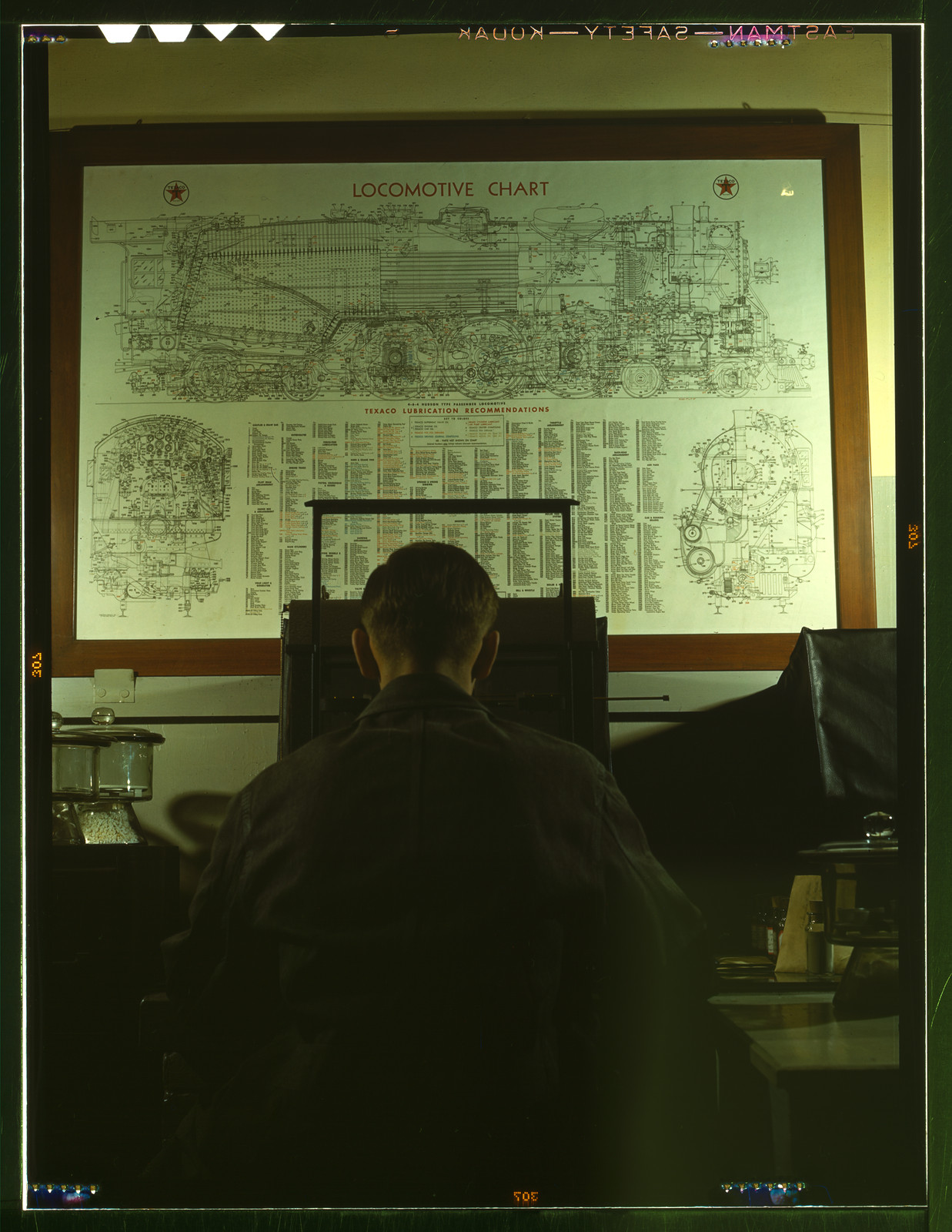 Man at desk before a Locomotive Chart with Texaco lubrication recommendations — historic image