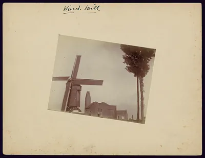 Windmill beside brick buildings and tall trees