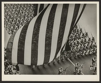 Soldiers marching beneath a giant American flag in a parade