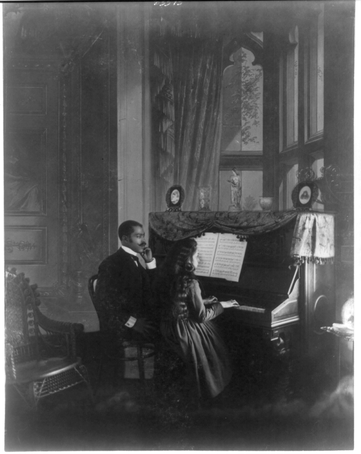 [African American man giving piano lesson to young African American woman], [1899 or 1900] — historic photograph