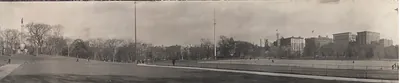 Panoramic sepia photo of a city park with flagpoles and buildings