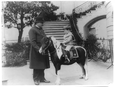 [Quentin Roosevelt on pony beside White House policeman]