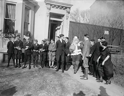 Boys gather around a Santa Claus figure outside a house