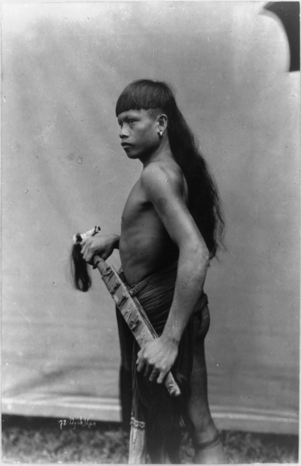 [Dyak man, Singapore, standing, three-quarter length portrait, facing left], [between ca. 1890 and 1925] — historic photograph